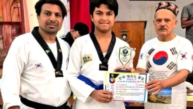 Three people at a martial arts ceremony: a young athlete of the National Taekwondo Club in a uniform holding a certificate between two coaches.