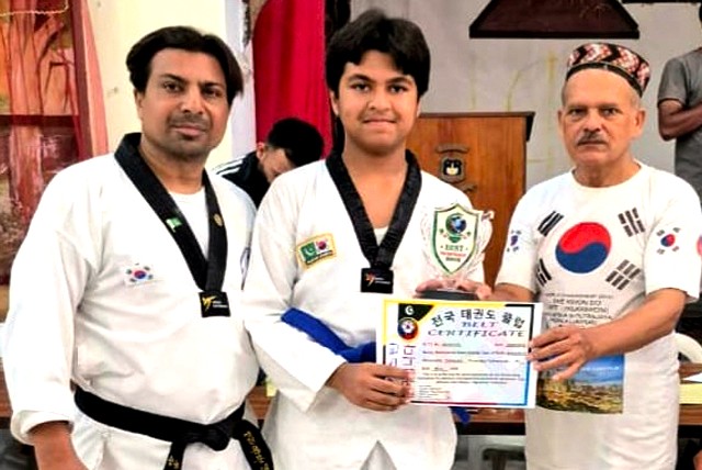 Three people at a martial arts ceremony: a young athlete of the National Taekwondo Club in a uniform holding a certificate between two coaches.