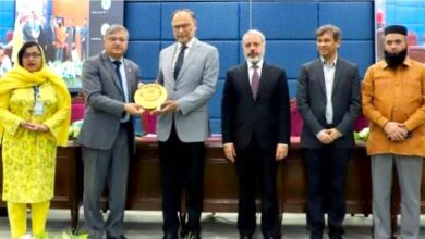 Federal Minister Ahsan Iqbal receiving a golden commemorative shield from AIOU Vice Chancellor Prof. Dr. Nasir Mahmood alongside other officials at an international conference ceremony.