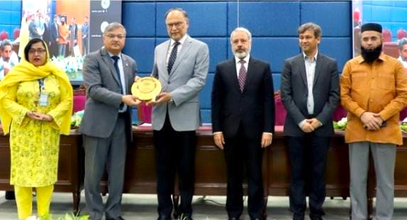 Federal Minister Ahsan Iqbal receiving a golden commemorative shield from AIOU Vice Chancellor Prof. Dr. Nasir Mahmood alongside other officials at an international conference ceremony.