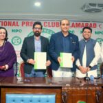 Roots Millennium Schools leadership and National Press Club officials standing behind a wooden desk, with Abdur Razzaq Sial and Dr Faisal Mushtaq holding signed green-and-white MoU documents in front of a National Press Club Islamabad backdrop.