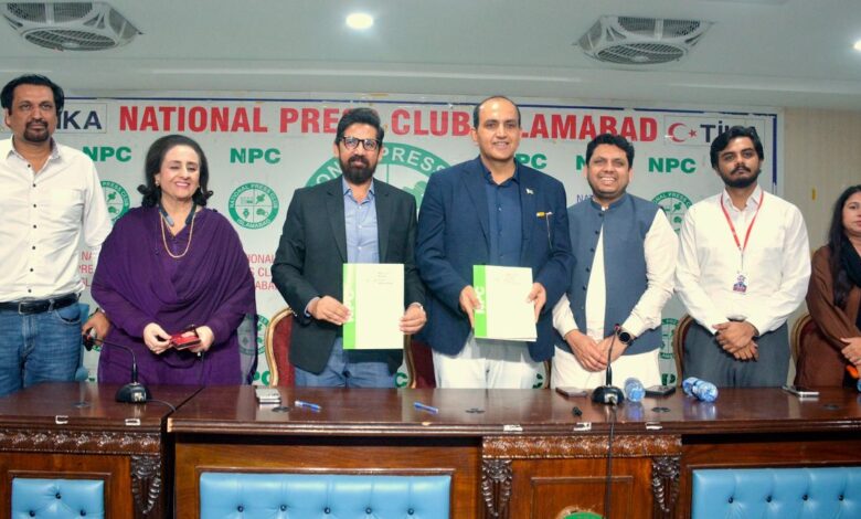 Roots Millennium Schools leadership and National Press Club officials standing behind a wooden desk, with Abdur Razzaq Sial and Dr Faisal Mushtaq holding signed green-and-white MoU documents in front of a National Press Club Islamabad backdrop.